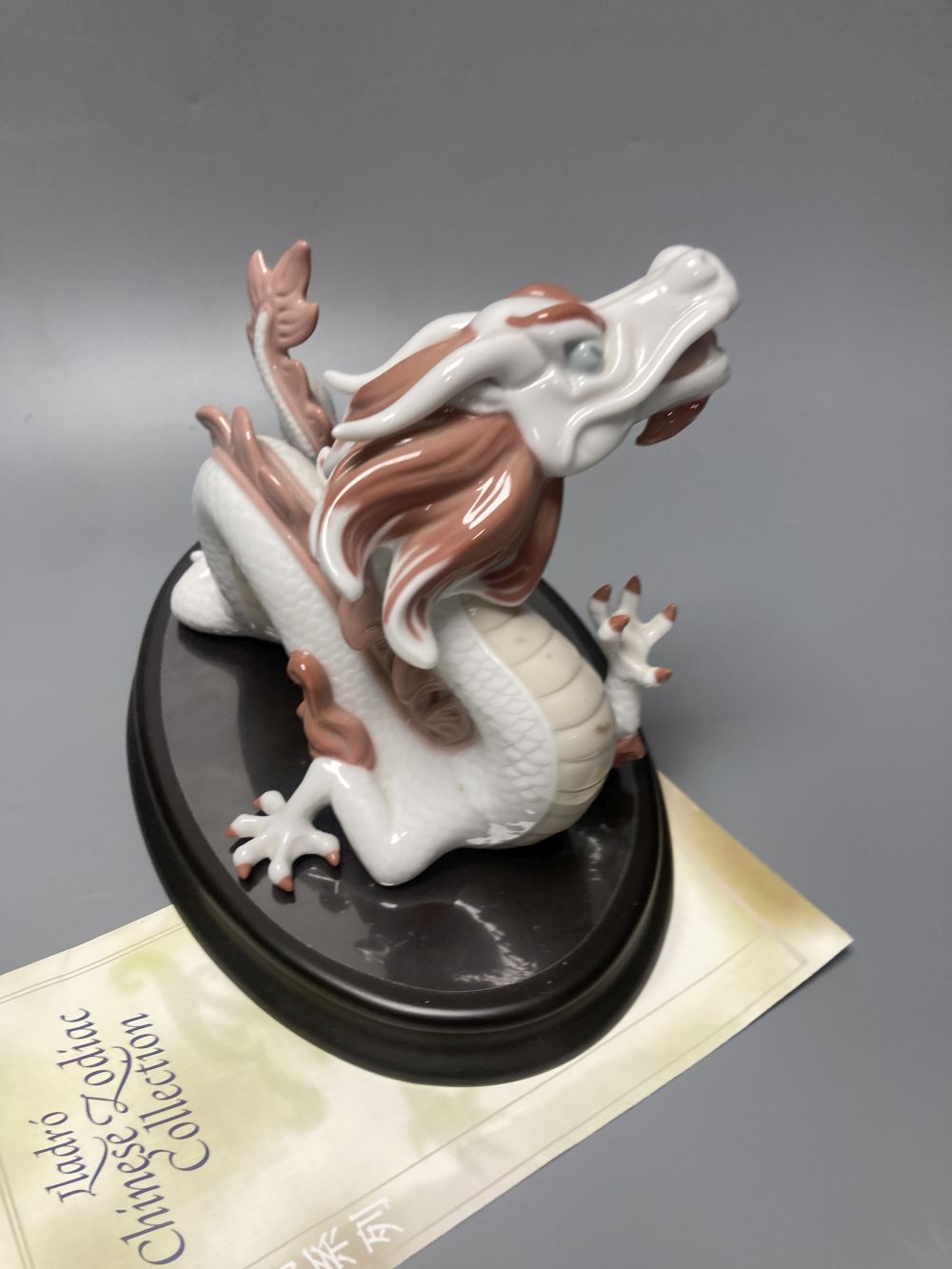 A Lladro porcelain model of a dragon, from the Chinese Zodiac collection, designed by John Coderch, width 16cm, with stand